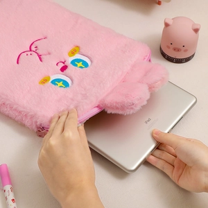 Gros plan de l'insertion d'un iPad dans une housse en peluche rose avec broderie