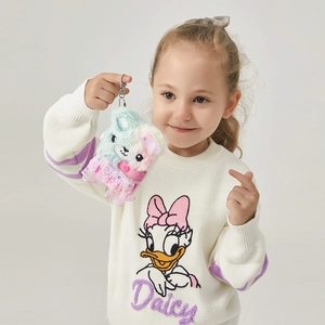 Rainbow plush bear keychain with pink lace dress held by a girl in a studio setting