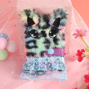 Close-up of pink plush notebook cover with cute cat embroidery and blue lace skirt details