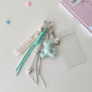 Detail of plush bear keychain with heart carabiner, lace ribbon, and blue strap