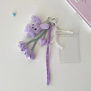 Macro detail of purple plush rabbit keychain with card holder and tulip floral accents