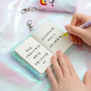 Primo piano del portachiavi quaderno in peluche unicorno con penna a righe colorate