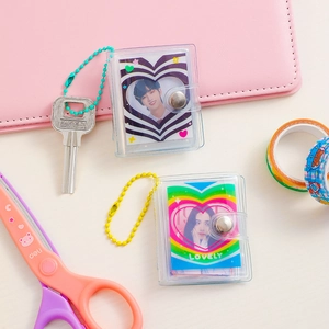 Close-up of mini transparent PVC photo album with heart patterns and colorful bead chain