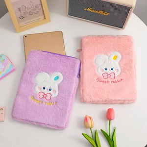Close-up of cute rabbit embroidery on pink and purple plush iPad sleeves on wooden desk