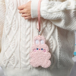 Pink plush bunny card holder with wrist strap and embroidery on white sweater background