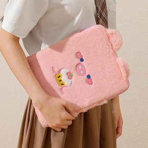 Detalle de funda de felpa rosa para tablet con bordado de cerdito sostenida por modelo