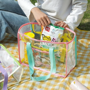 Detailed outdoor view of a large clear PVC tote bag with mesh panels and pink trim