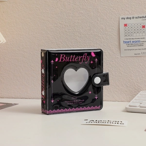 Macro view of black patent leather mini photo album with heart cutout and Butterfly print