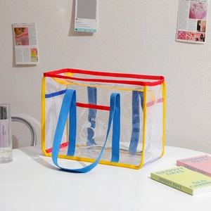 Close-up of clear PVC and mesh tote bag with colorful handles and cartoon print