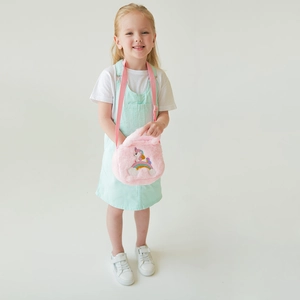 Sac à bandoulière licorne en peluche rose avec broderie arc-en-ciel porté par une fille