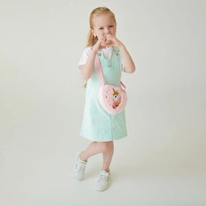 Detailed close-up of a pink plush unicorn heart bag held by a girl in studio light