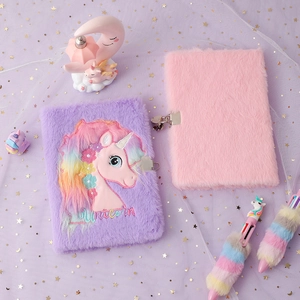 Close-up of plush unicorn notebooks and matching pens on starry mesh background