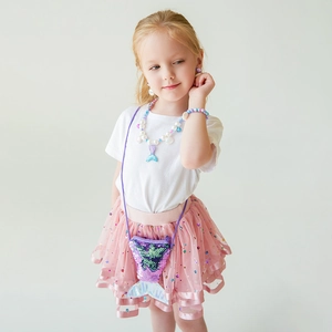 Detailed view of child model wearing sequined mermaid tail bag and beaded jewelry set