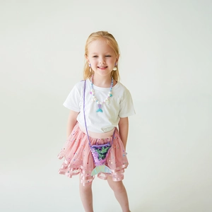 Girl wearing mermaid jewelry set with sequin shell bag and beaded pearl necklace