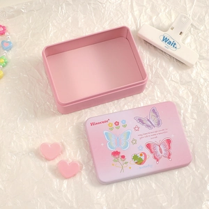 Close-up of pink tin storage box with floral patterns and butterfly illustrations