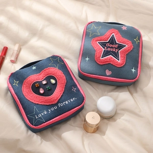 Denim square makeup bags with embroidered hearts and stars on beige fabric background
