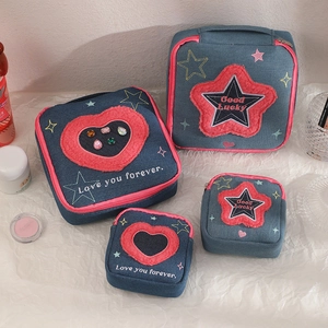 Detail of embroidered denim makeup bags with pink heart patches and zipper accents