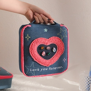 Denim makeup bag with pink heart patch and star embroidery featuring a top handle