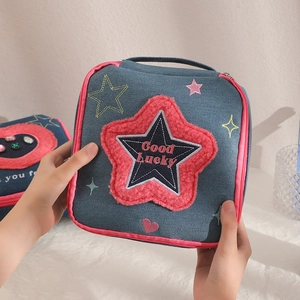 Detail of blue denim cosmetic bag with pink plush star embroidery and top handle