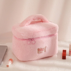 Détail d'une trousse à maquillage rose en peluche avec poignée et double fermeture