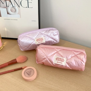 Detailed close-up of quilted metallic makeup bags with inspirational labels on wood