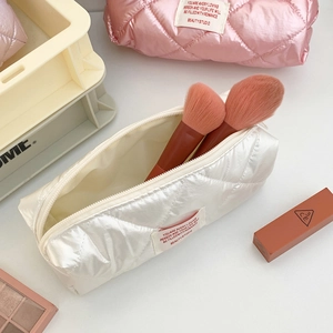 Quilted cosmetic bag with pearl finish showing cream and pink makeup organizers