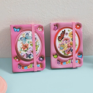 Detail of pink mini pocket journals with floral butterfly patterns and elastic bands