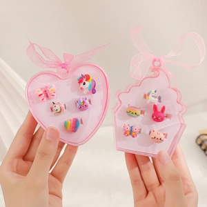 Detail of cute unicorn and rainbow rings in pink heart-shaped and cupcake gift boxes