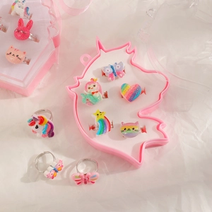 Macro detail of cartoon rings with unicorn, mermaid, and heart in a pink storage box