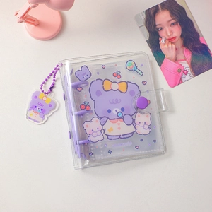 Detail of purple cartoon bear PVC 3-ring binder album with matching charm on white desk
