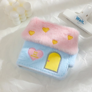 Gros plan sur l'étui en peluche en forme de maison avec broderies de cœurs colorés