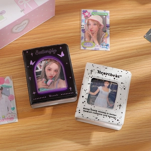 Top view of butterfly and heartbeat themed photocard albums on a natural wooden surface