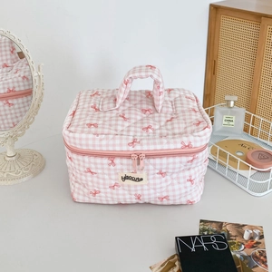 Vue détaillée de la trousse de maquillage matelassée à carreaux roses et nœuds rouges