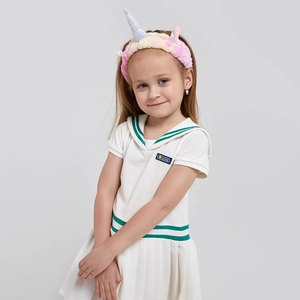 Détail de la robe de marin blanche à rayures vertes et du serre-tête licorne en peluche