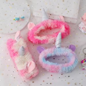 Vue détaillée de bandeaux licorne en peluche rose et bleue avec des cornes à paillettes