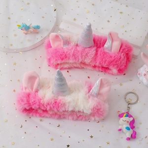 Détail de bandeaux licorne en peluche avec cornes argentées et oreilles roses sur tulle étoilé