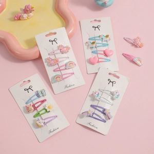 Dettaglio di set 4 mollette per capelli unicorno e arcobaleno su sfondo rosa