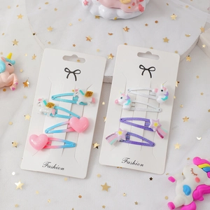Dettaglio di 4 fermagli per capelli con unicorno e arcobaleno su sfondo in tulle bianco