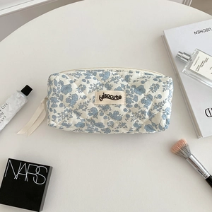 Close-up of quilted floral cosmetic bag with blue flower pattern and zipper ribbon detail
