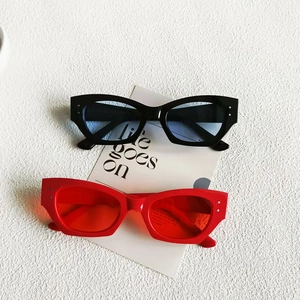Detail of cat eye sunglasses with metal studs and vibrant lenses on a textured wall