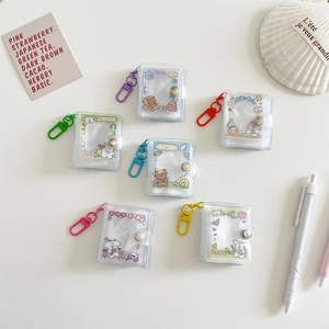 Flat lay of colorful mini PVC photo albums with cartoon designs and matching carabiners