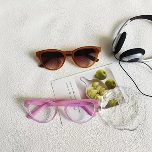 Retro cat-eye amber sunglasses and pink clear frame glasses on a stylish white desk