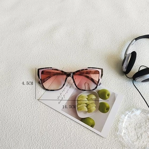 Close-up of pink cat eye sunglasses with tortoise pattern and gradient lenses on white fabric