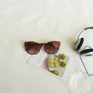 Detail of retro cat-eye sunglasses with tortoise frame on a white textured background