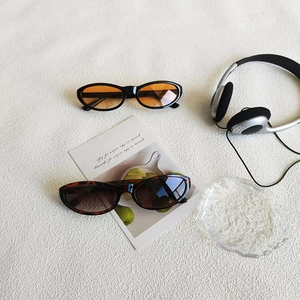 Retro cat eye sunglasses with orange and tortoiseshell frames on a white fabric surface