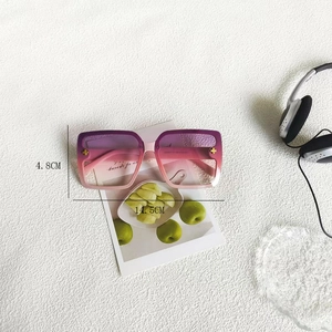 Macro detail of square oversized sunglasses showing dimensions and floral gold ornaments
