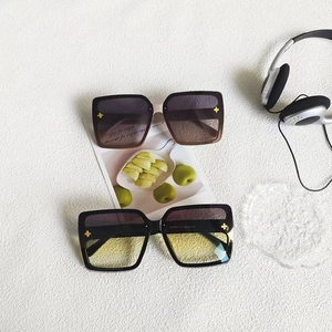 Detail of square oversized sunglasses with golden cross rivets on the gradient lenses