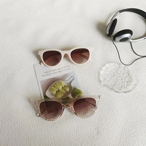 Macro view of matte cream and champagne cat eye sunglasses with gradient brown lenses