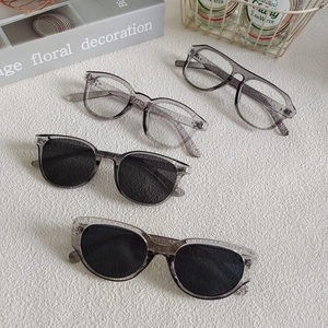 Group of four trendy translucent grey square sunglasses and frames in a lifestyle setting