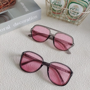 Detail view of grey translucent frames with pink tinted lenses on a stylish backdrop